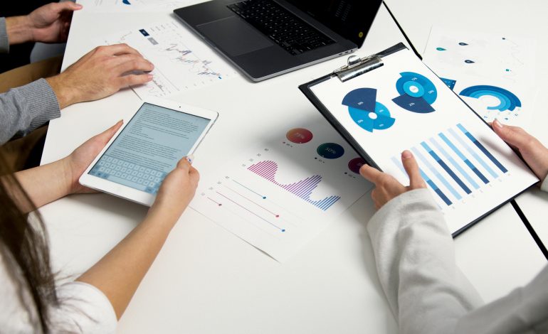 A team analyzing digital marketing reports with charts, graphs, and a tablet.