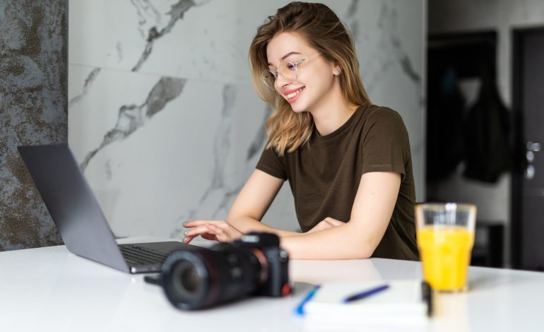 A young woman working on her laptop in a modern setting, representing a productive guest blogging space.