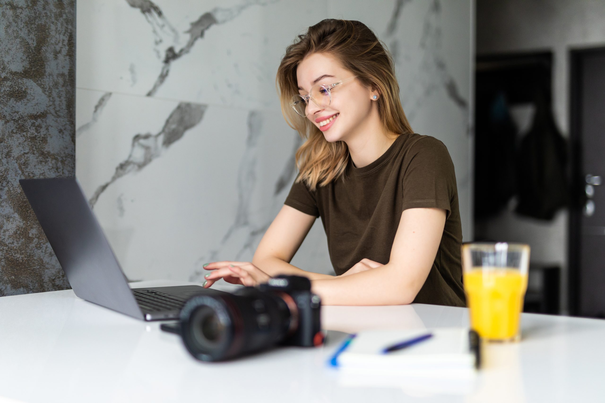 A young woman working on her laptop in a modern setting, representing a productive guest blogging space.